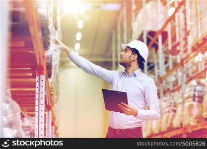 wholesale, logistic, business, export and people concept - happy man or manager with clipboard checking goods at warehouse. happy businessman with clipboard at warehouse