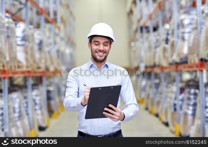 wholesale, logistic, business, export and people concept - happy man or manager with clipboard checking goods at warehouse