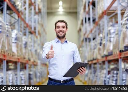 wholesale, logistic, business, export and people concept - happy man with clipboard at warehouse showing thumbs up gesture