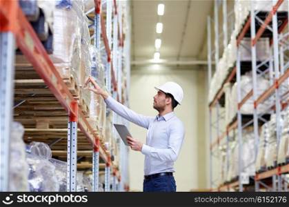 wholesale, logistic, business, export and people concept - man or manager in hardhat with tablet pc computer checking goods at warehouse