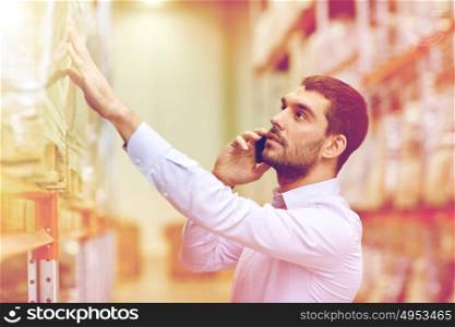 wholesale, logistic, business, export and people concept - serious businessman calling on smartphone at warehouse. serious man calling on smartphone at warehouse