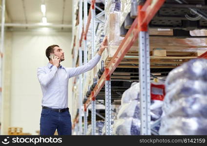 wholesale, logistic, business, export and people concept - serious businessman calling on smartphone at warehouse