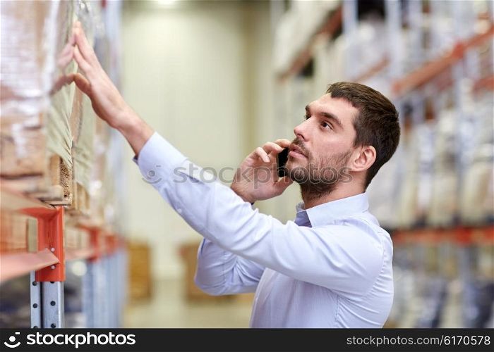 wholesale, logistic, business, export and people concept - serious businessman calling on smartphone at warehouse