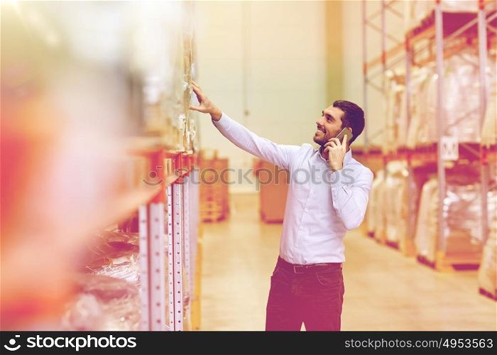 wholesale, logistic, business, export and people concept - smiling businessman calling on smartphone at warehouse. happy man calling on smartphone at warehouse