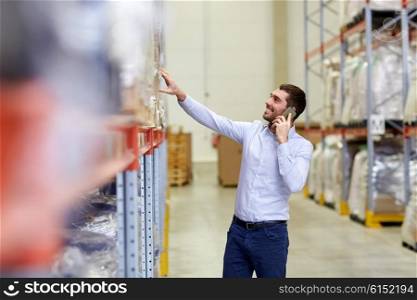 wholesale, logistic, business, export and people concept - smiling businessman calling on smartphone at warehouse