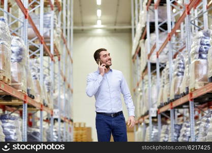 wholesale, logistic, business, export and people concept - smiling businessman calling on smartphone at warehouse