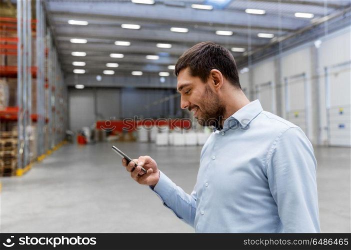 wholesale, logistic business, technology and people concept - businessman with smartphone at warehouse. businessman with smartphone at warehouse. businessman with smartphone at warehouse