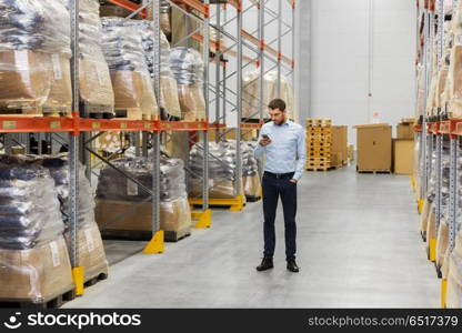 wholesale, logistic business, technology and people concept - businessman with smartphone at warehouse. businessman with smartphone at warehouse. businessman with smartphone at warehouse