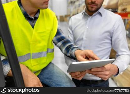 wholesale, logistic, loading, shipment and people concept - close up of loader on forklift and businessman with tablet pc computer at warehouse. men with tablet pc and forklift at warehouse