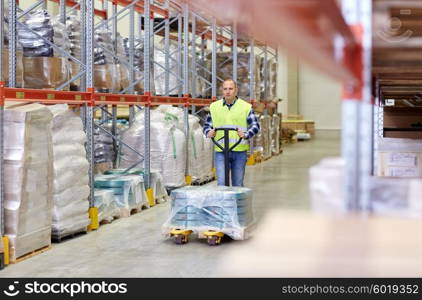 wholesale, logistic, loading, shipment and people concept - man carrying loader with goods at warehouse