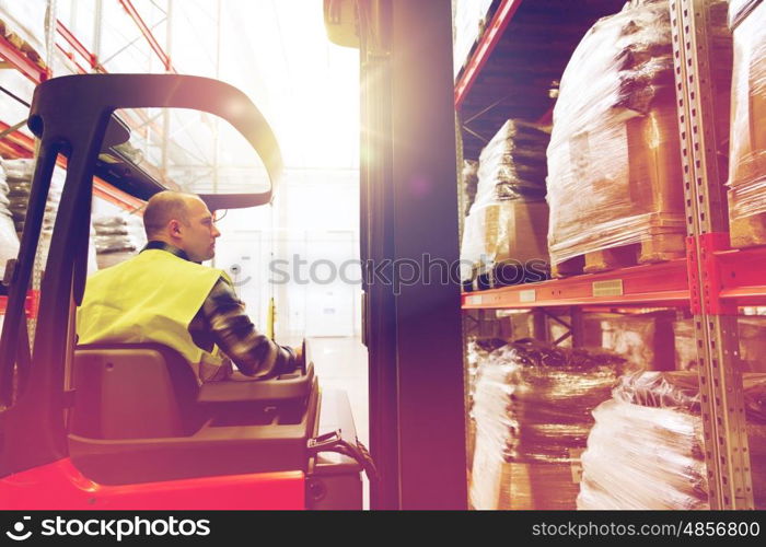 wholesale, logistic, loading, shipment and people concept - man or loader operating forklift loader at warehouse