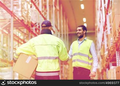 wholesale, logistic, people, agreement and export concept - manual worker and businessmen in reflective safety vests shaking hands and making deal at warehouse. men in safety vests shaking hands at warehouse
