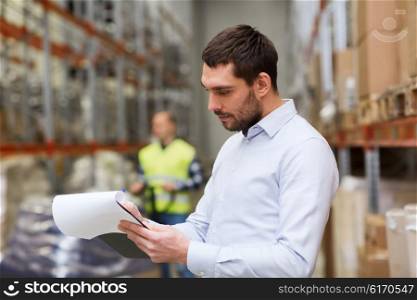 wholesale, logistic, people and export concept - businessman or supervisor with clipboards at warehouse
