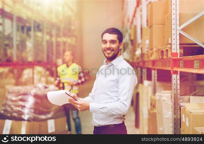 wholesale, logistic, people and export concept - happy businessman or supervisor with clipboards at warehouse