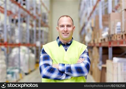 wholesale, logistic, people and export concept - happy man in reflective safety vest at warehouse