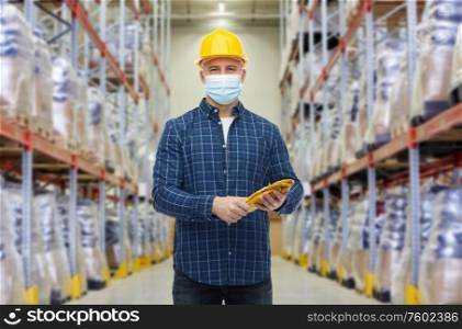 wholesale, logistic, people and export concept - male worker in safety helmet wearing face protective medical mask over warehouse background. male worker wearing face mask at warehouse
