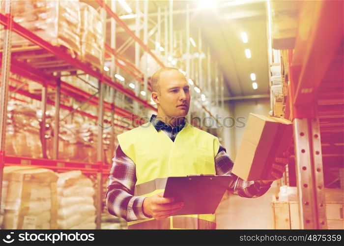 wholesale, logistic, people and export concept - man with clipboard and box in reflective safety vest at warehouse