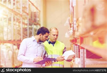 wholesale, logistic, people and export concept - manual worker and businessmen with clipboard and box at warehouse