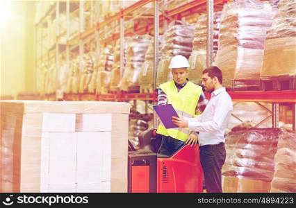 wholesale, logistic, people and export concept - manual worker and businessmen with clipboard at warehouse