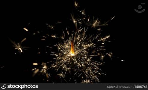 Wick with lit gunpowder from which many sparks come out on black background