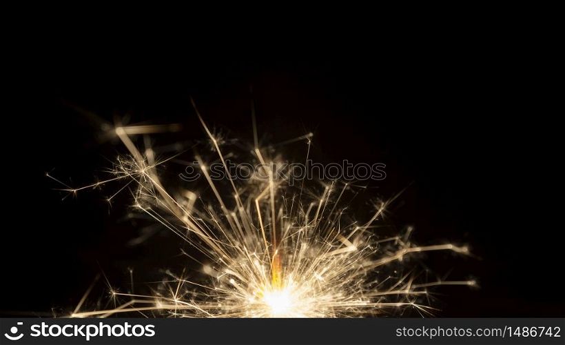Wick with lit gunpowder from which many sparks come out on black background