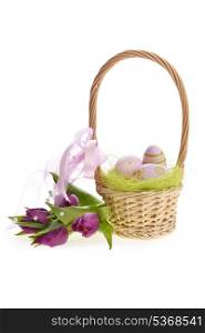 wicker basket of easter eggs with purple tulips