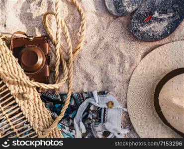 Wicker basket, vintage camera and shawl lying on a background of sand. Top view, close-up. Wicker basket, vintage camera and shawl on sand