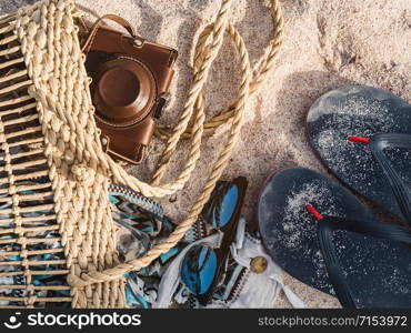 Wicker basket, vintage camera and shawl lying on a background of sand. Top view, close-up. Wicker basket, vintage camera and shawl on sand