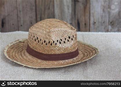 Wicker hat on brown fabric and wooden background