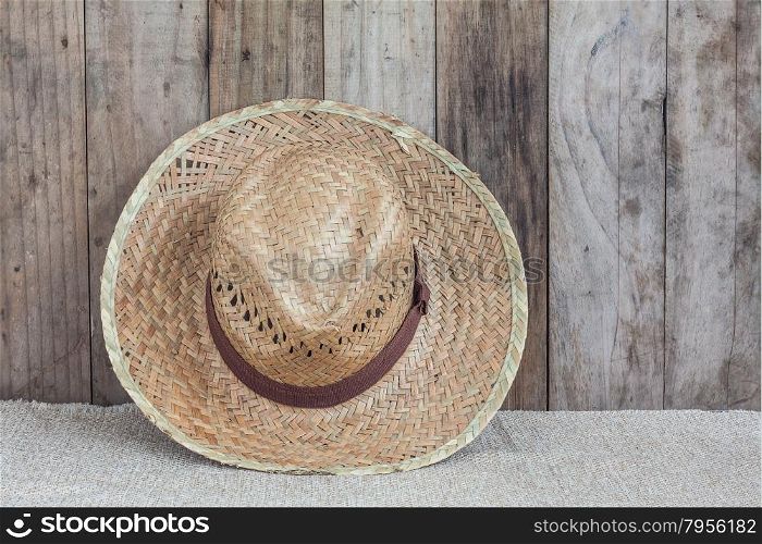 Wicker hat on brown fabric lean against wooden background,