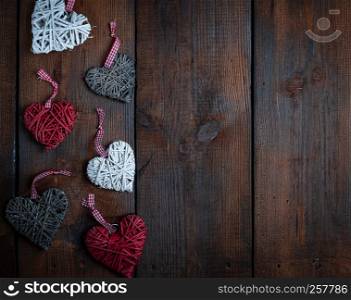 wicker hearts on a brown wooden plank background, empty space