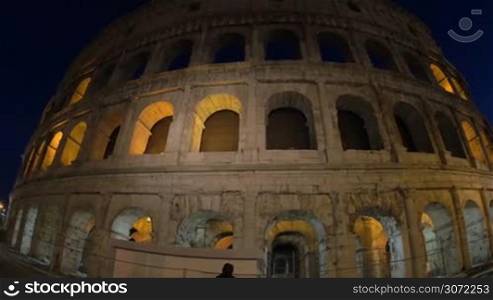 Wide angle and dolly shot of ancient Coliseum illuminated at night. Sightseeing of Rome, Italy