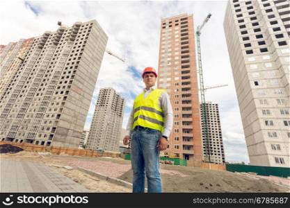 Wide angle portrait of young construction foreman standing on building site
