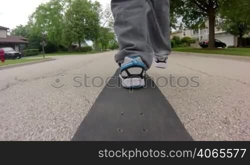 Wide angle shot from the back of a skateboard as a person skates down the street.