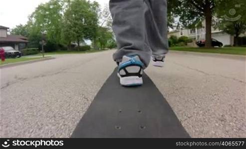 Wide angle shot from the back of a skateboard as a person skates down the street.