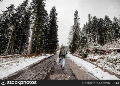 wide angle. tourist man with a backpack going through a snowy forest.. tourist man with a backpack going through a snowy forest. wide angle