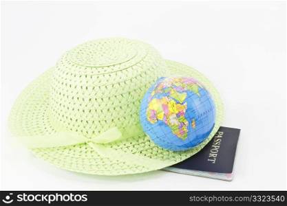 Wide-brimmed, light green, straw hat is placed with a small glove on its rim and a passport beneath.