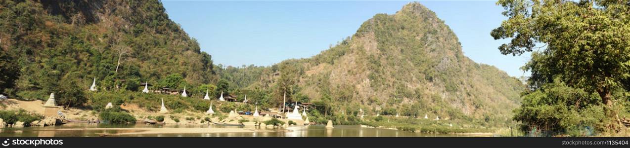 wide panoramic view of a river on the border between Thailand and Myanmar with white stupas and pagodas along the hillside, Northern Thailand, Southeast Asia
