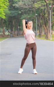 Wide shot and portrait of Asian sport woman do arm and back stretching on road of park during exercise in the morning.
