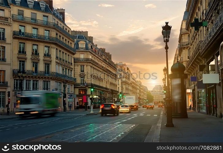 Wide street with road and beautiful architecture in Paris at sunrise, France