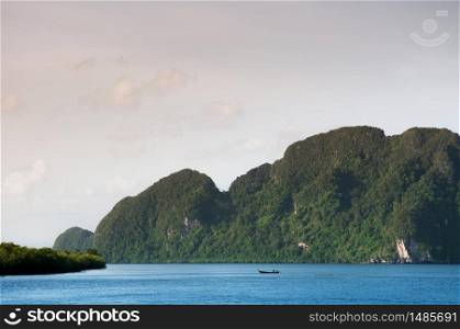 Wide view of Koh Lanta bay and islands in Krabi, Thailand with small fishing boat in evening.