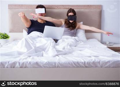 Wife and husband with virtual reality goggles in the bed