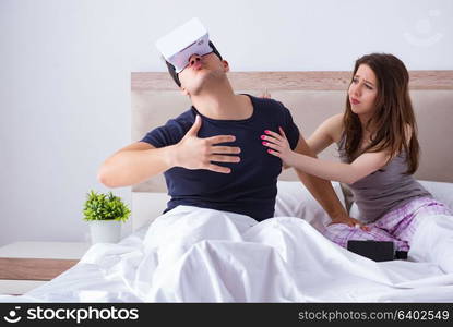 Wife and husband with virtual reality goggles in the bed