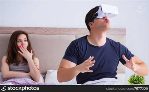 Wife and husband with virtual reality goggles in the bed. The wife and husband with virtual reality goggles in the bed