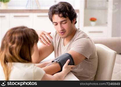 Wife checking husband&rsquo;s blood pressure  