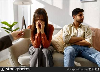 Wife crying while husband revert his eyes. Couple with problems during psychotherapy session. Wife crying, husband revert eyes during psychotherapy