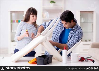 Wife helping husband to repair broken chair at home