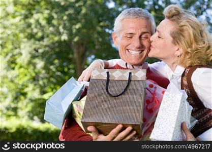 Wife kissing husband with bags of gifts