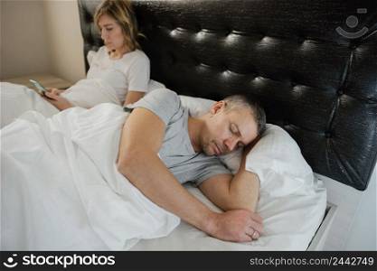 wife using mobile while husband is asleep 3