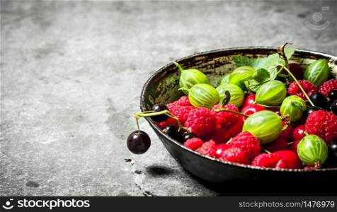Wild berries in the old plate. On the stone table.. Wild berries in the old plate. On stone table.